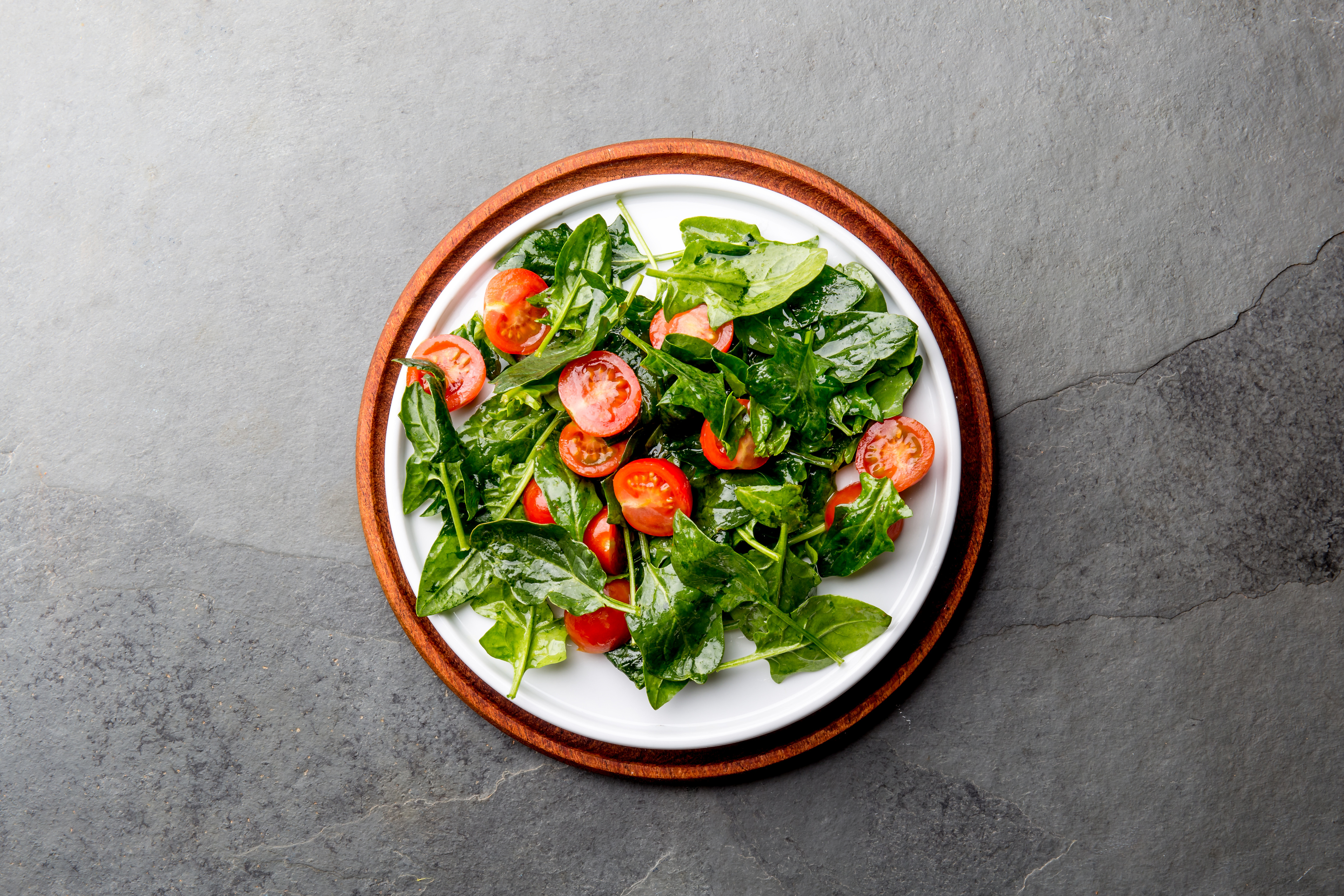 Fresh Summer Salad with Baby Spinach and Tomatoes Cherry. Top View, Copy Space. Slate Gray Background